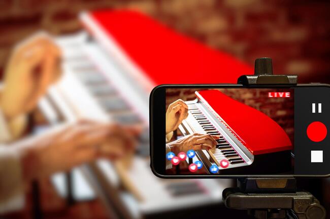 A YouTuber recording themselves playing a piano.