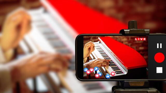 A YouTuber recording themselves playing a piano.